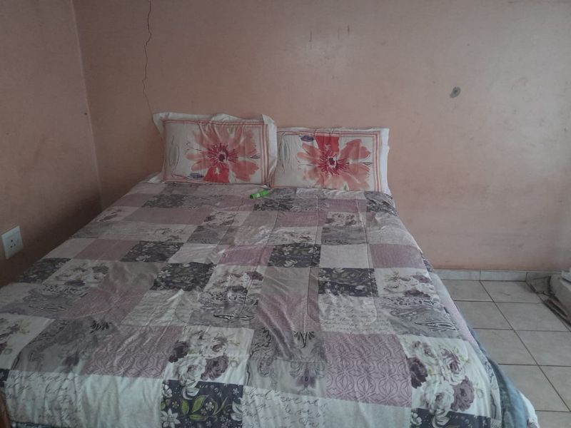 A bedroom featuring tiled flooring and walls showing signs of cracking and surface wear, requiring maintenance and cosmetic updates.