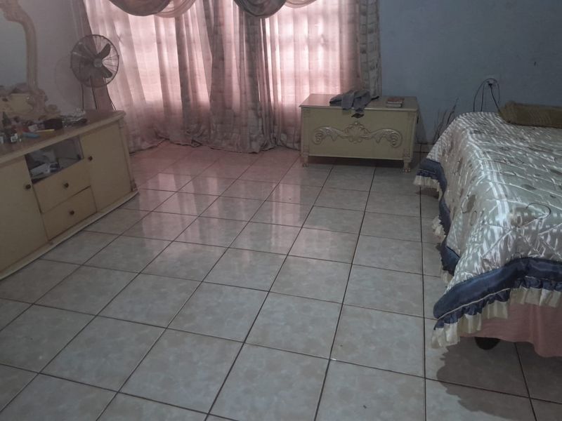 A bedroom featuring neutral ceramic floor tiles and window treatments, offering a functional space ready for personalization.
