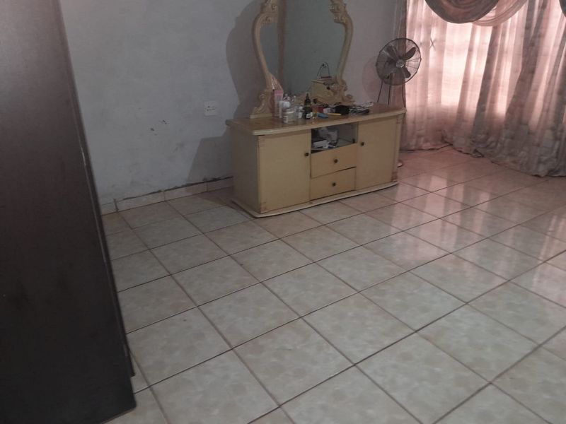 A bedroom featuring light-colored ceramic floor tiles and plain wall finishes, providing a neutral base for potential interior updates.