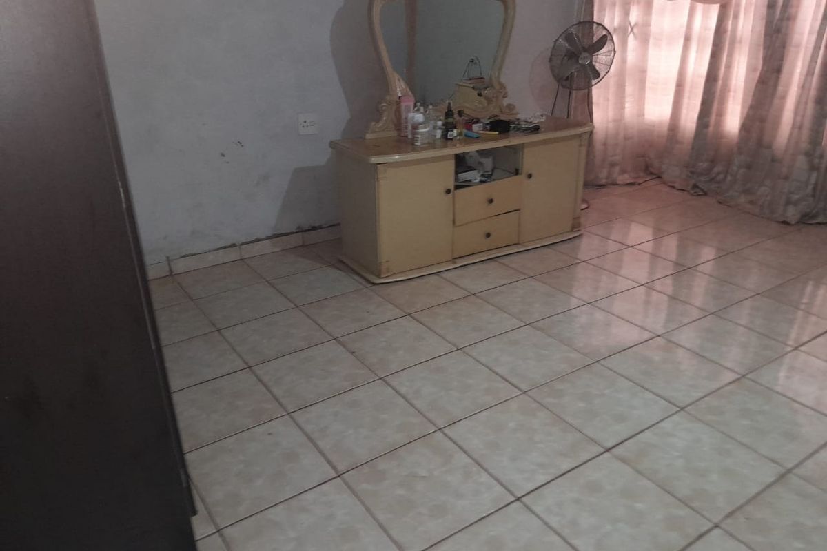 A bedroom featuring light-colored ceramic floor tiles and plain wall finishes, providing a neutral base for potential interior updates.
