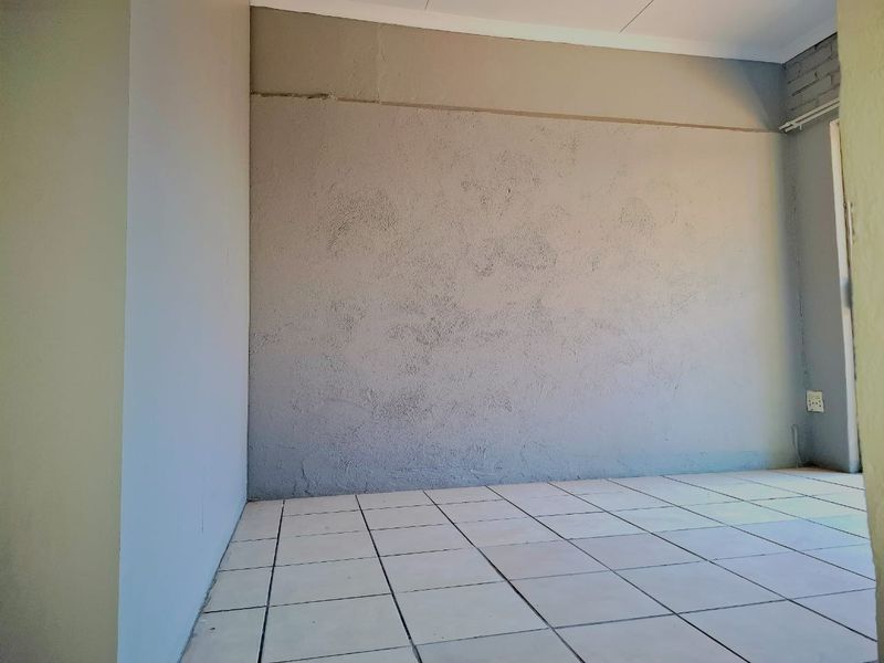 An empty bedroom featuring tiled flooring and a textured wall finish, presenting a blank canvas for renovation or interior design updates.