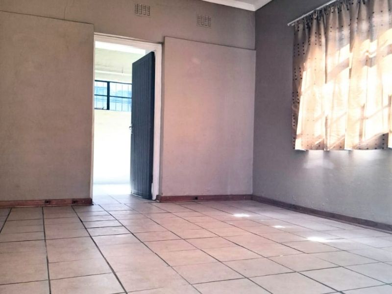 An empty living room featuring tiled flooring, neutral wall paint, and classic cornice detailing, offering a blank canvas for interior design.