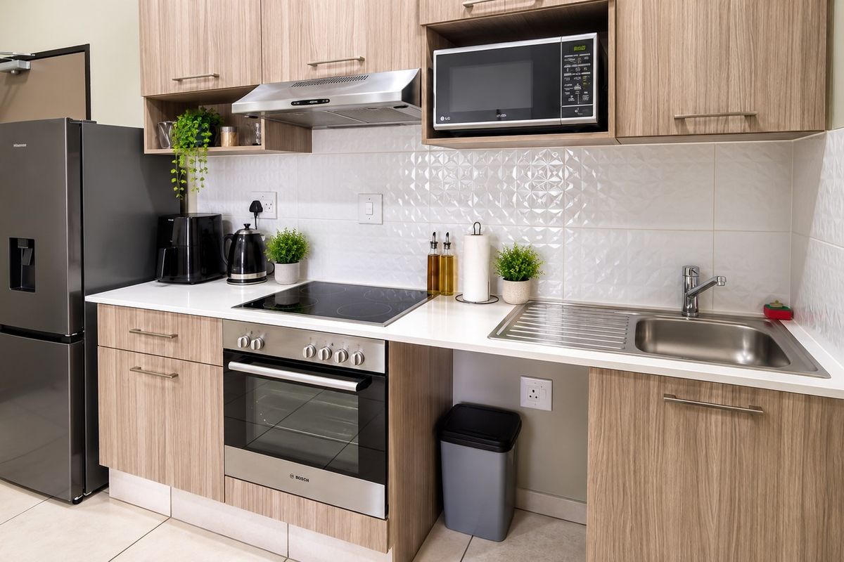Modern kitchen featuring light wood-grain cabinetry, stone countertops, a tiled backsplash, and integrated stainless steel appliances including an oven, hob, and extractor fan.
