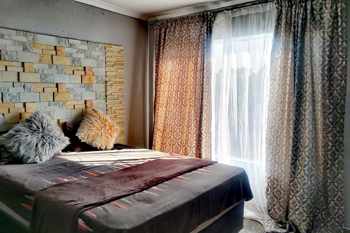 Bedroom featuring a decorative stone accent wall and a sliding glass door providing natural light.