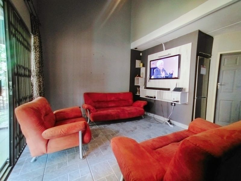 Living room featuring tiled flooring, a built-in media console, and high ceilings with access to an exterior area via a security gate.