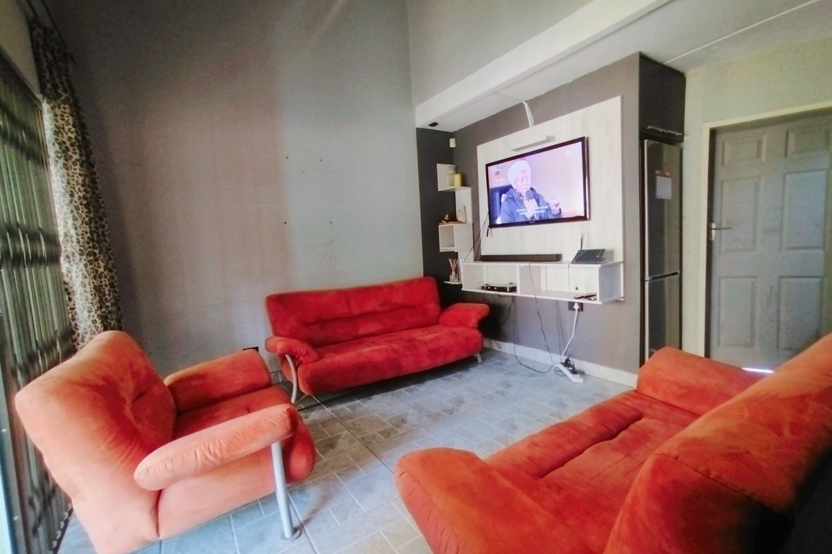 A living room featuring tiled flooring, high ceilings, and a built-in media console with wall-mounted television.