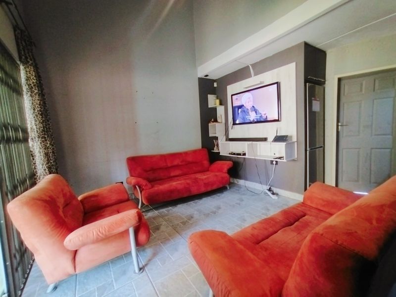 A living room featuring tiled flooring, high ceilings, and a built-in media console with wall-mounted television.