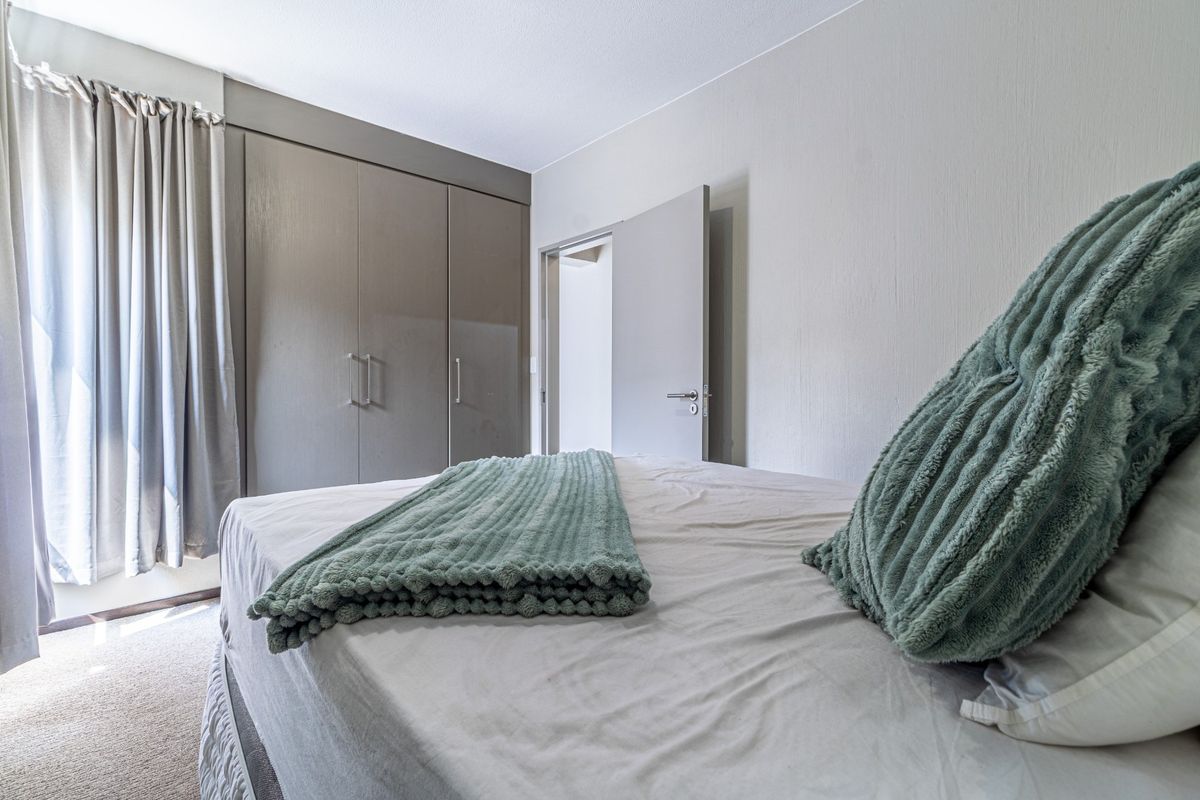 A well-maintained bedroom featuring neutral walls, carpeted flooring, and ample built-in cupboard storage space.