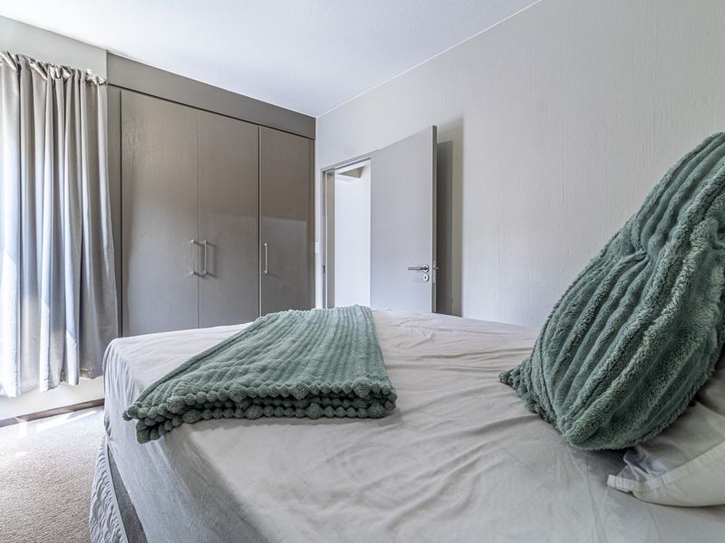 A well-maintained bedroom featuring neutral walls, carpeted flooring, and ample built-in cupboard storage space.