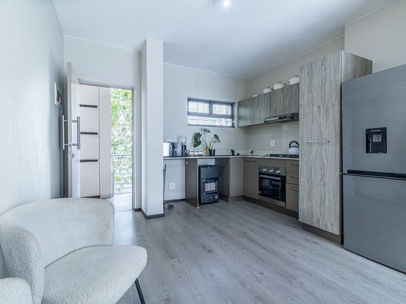 Open-plan kitchen featuring modern cabinetry, built-in oven, and gas hob, with direct access to a balcony area.