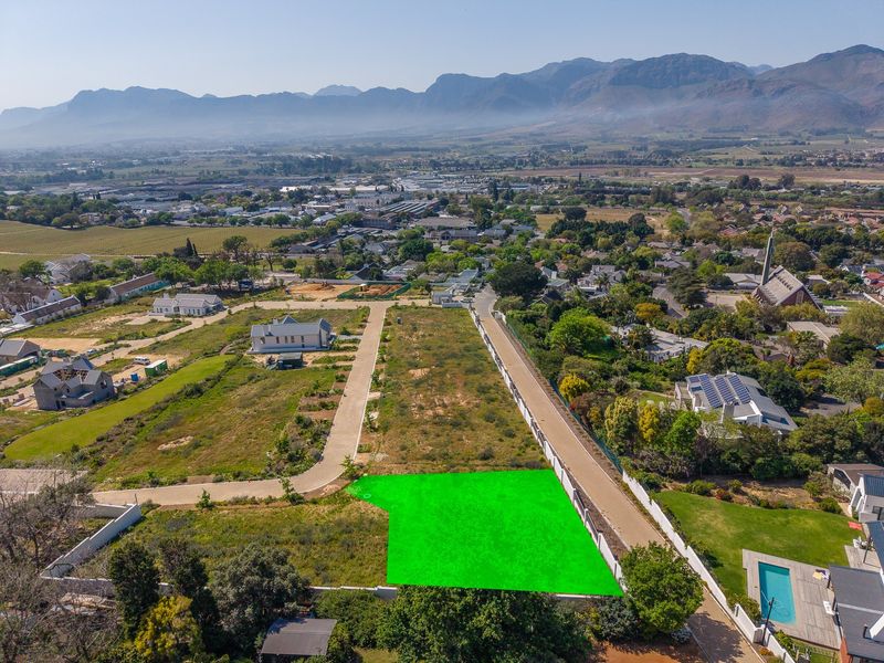 Aerial view of a vacant residential plot featuring clear boundary lines, paved access, and surrounding established neighborhood infrastructure.