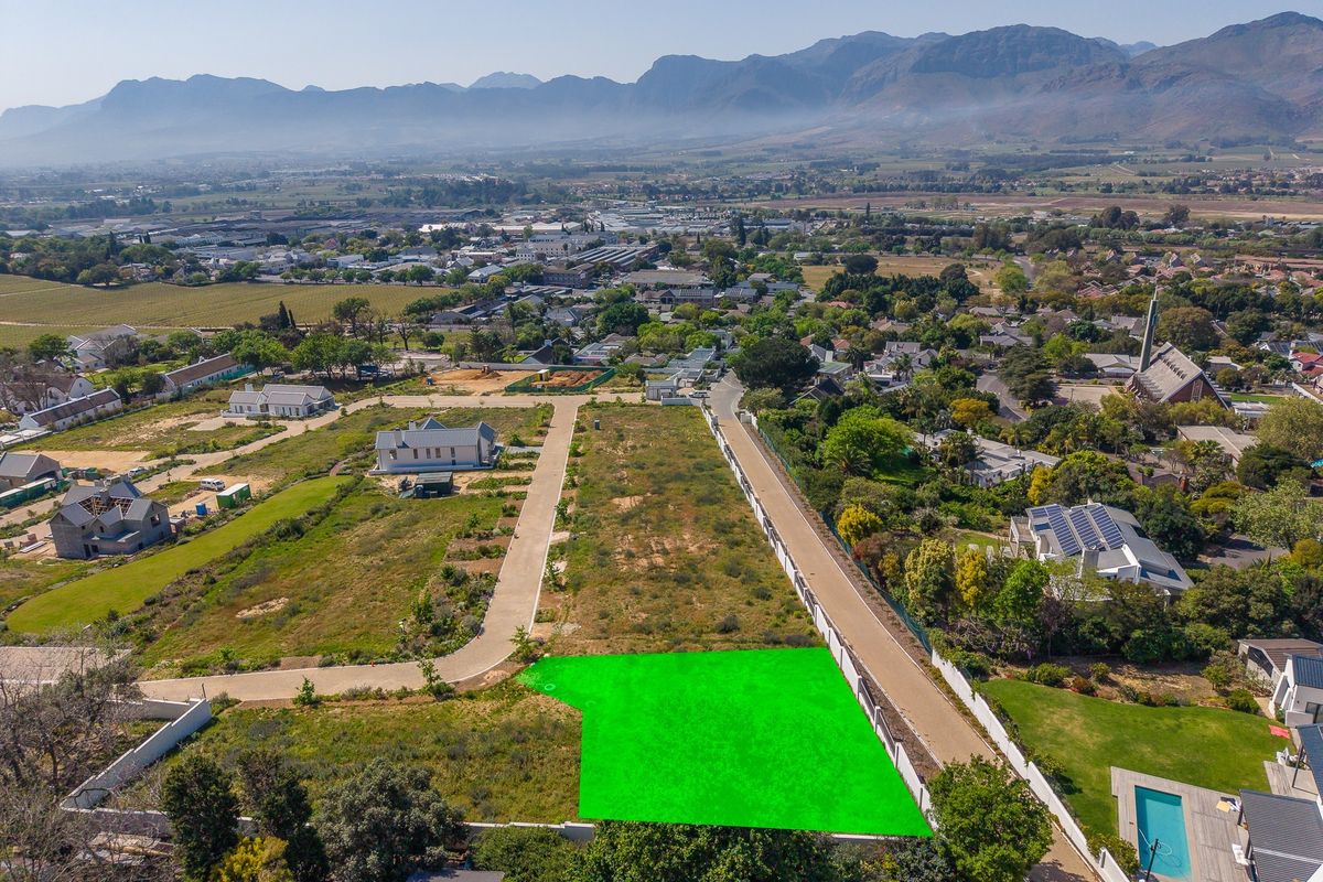 Aerial view of a vacant residential plot featuring clear boundary lines, paved access, and surrounding established neighborhood infrastructure.