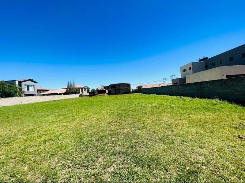 A vacant residential plot featuring a level grass lawn enclosed by boundary walls, situated within a developed neighborhood.