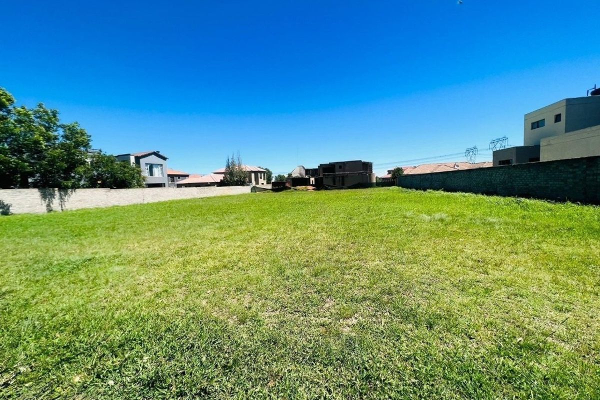 A vacant residential plot featuring a level grass lawn enclosed by perimeter boundary walls in a developed neighborhood.