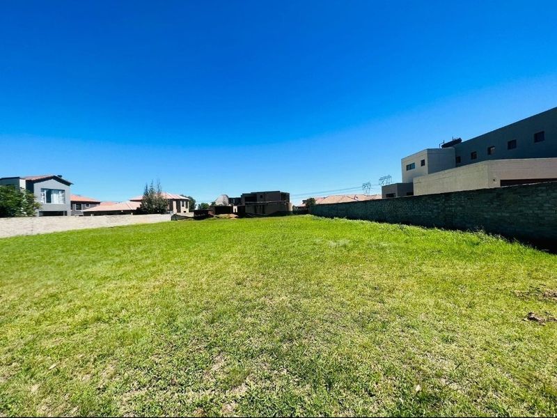 A spacious, level vacant residential plot featuring established lawn and perimeter boundary walls in a developed neighborhood.