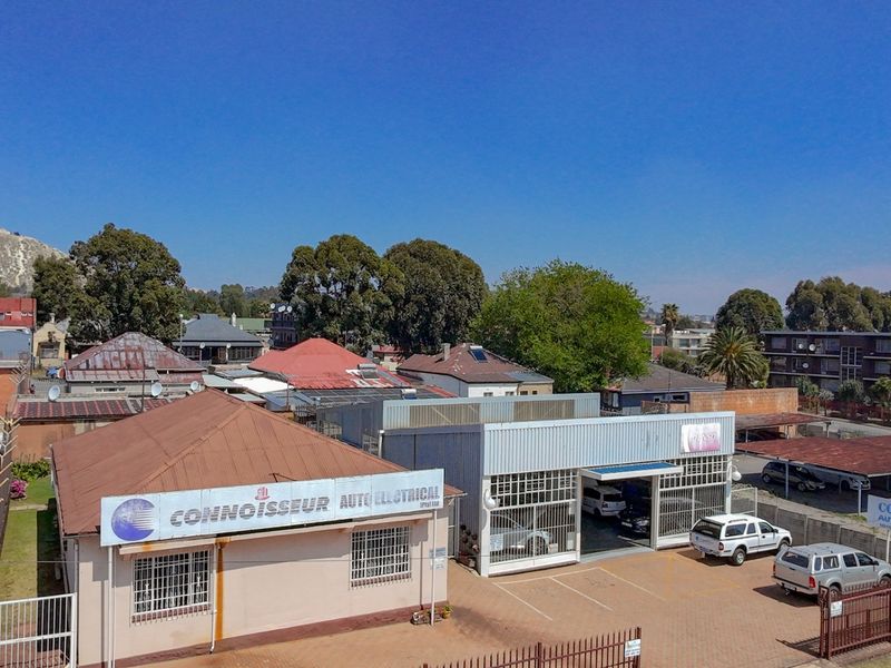 Aerial view of a commercial auto electrical workshop featuring multiple buildings, paved parking areas, and secure perimeter fencing in an urban setting.