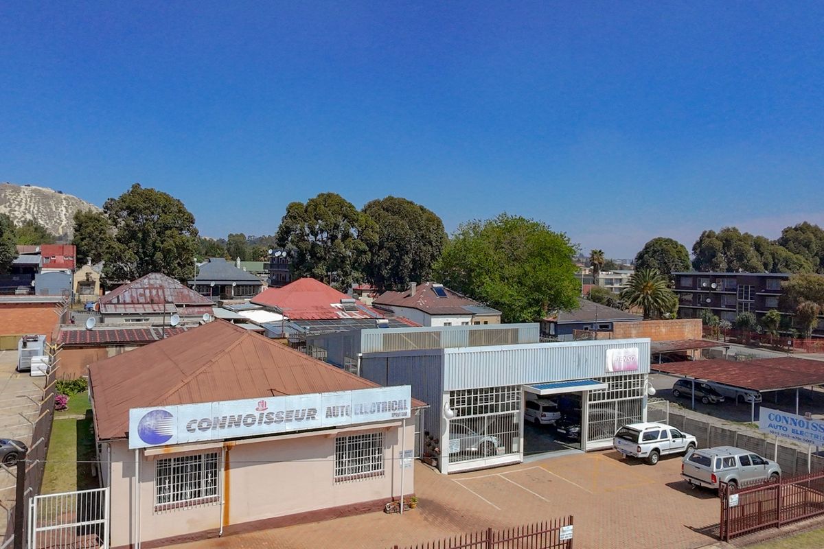 Aerial view of a commercial auto electrical workshop featuring multiple buildings, paved parking areas, and secure perimeter fencing in an urban setting.