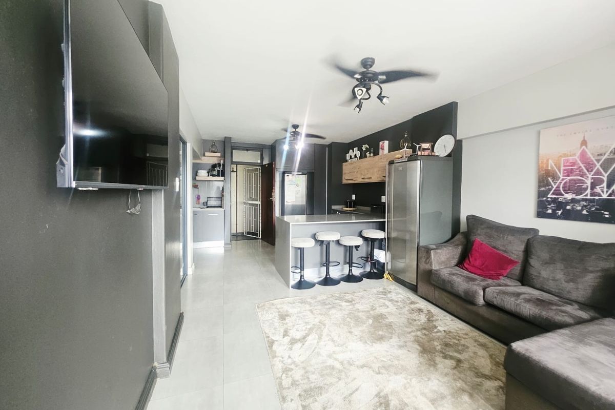 Open-plan living area featuring a modern kitchen with a central island, breakfast bar, and tiled flooring throughout.