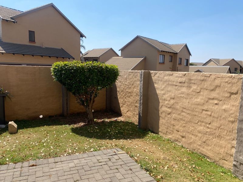 A private rear garden area featuring a paved patio, lawn, and high boundary walls, providing a secure outdoor space.