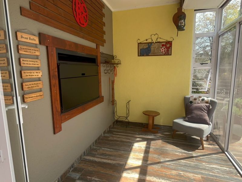 Enclosed patio area featuring a built-in braai, timber wall accents, and large sliding glass doors providing natural light and garden views.