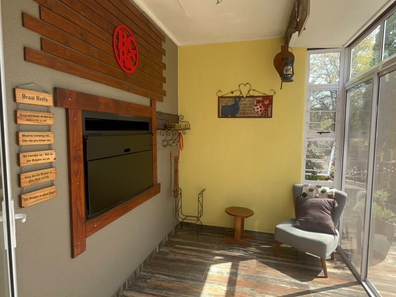 Enclosed patio area featuring a built-in fireplace, timber wall accents, tiled flooring, and large aluminium sliding doors providing natural light and garden views.