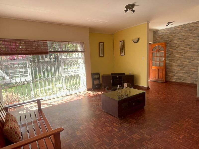 Spacious living room featuring classic parquet flooring, a textured stone feature wall, and large sliding doors providing access to the garden.