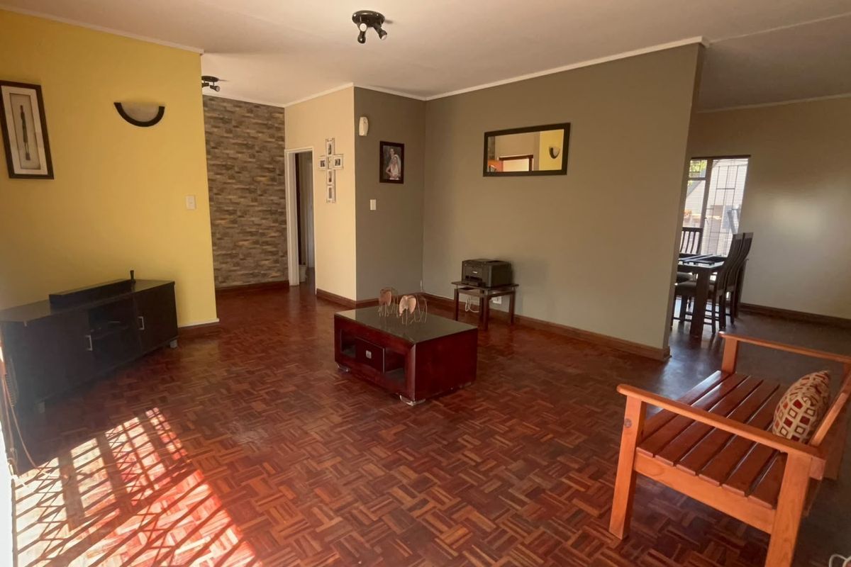 Spacious living area featuring classic parquet flooring and a decorative stone-clad feature wall, offering a warm and inviting atmosphere.