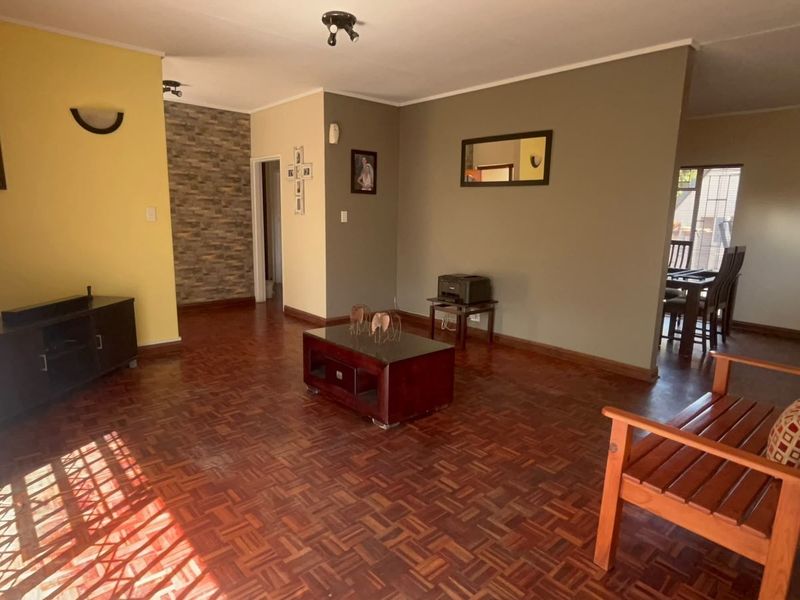 Spacious living area featuring classic parquet flooring and a decorative stone-clad feature wall, offering a warm and inviting atmosphere.