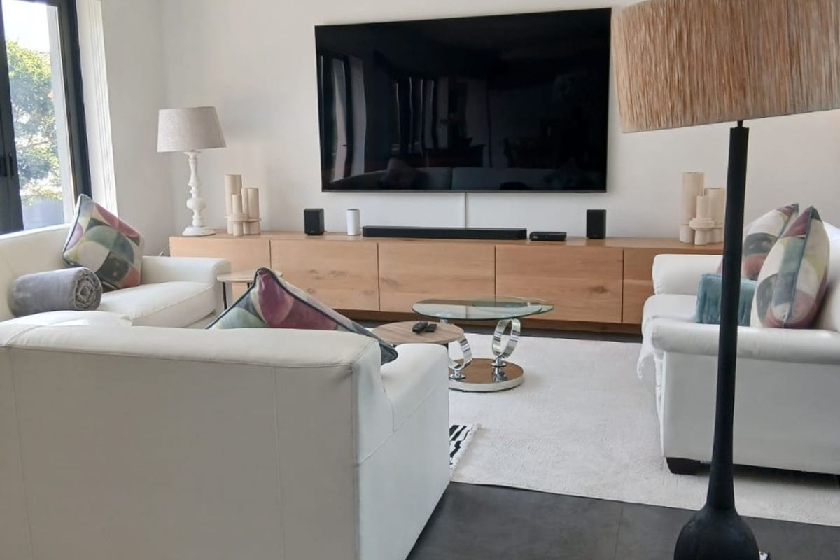 A modern, well-maintained living room featuring large-format floor tiles, recessed ceiling lighting, and custom built-in cabinetry for media storage.