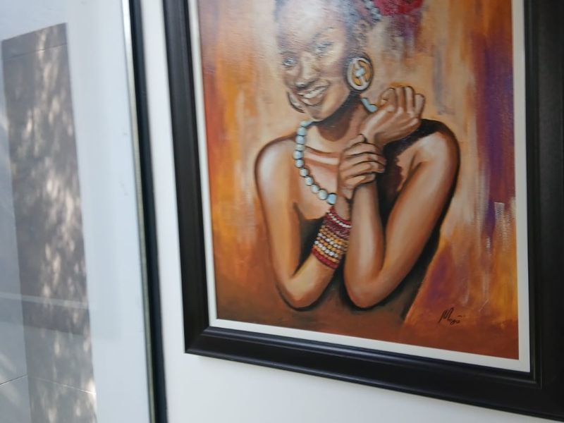 A close-up view of a framed portrait painting hanging on an interior wall.