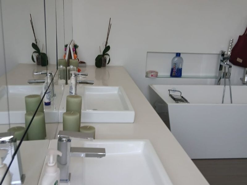 Modern bathroom featuring a double vanity with integrated sinks, a sleek freestanding bathtub, and a recessed wall niche for storage.
