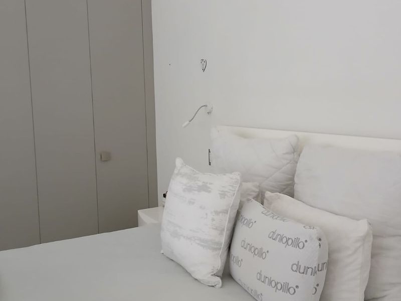 A bedroom featuring neutral-toned built-in wardrobes and a wall-mounted reading light, presenting a clean and functional space.