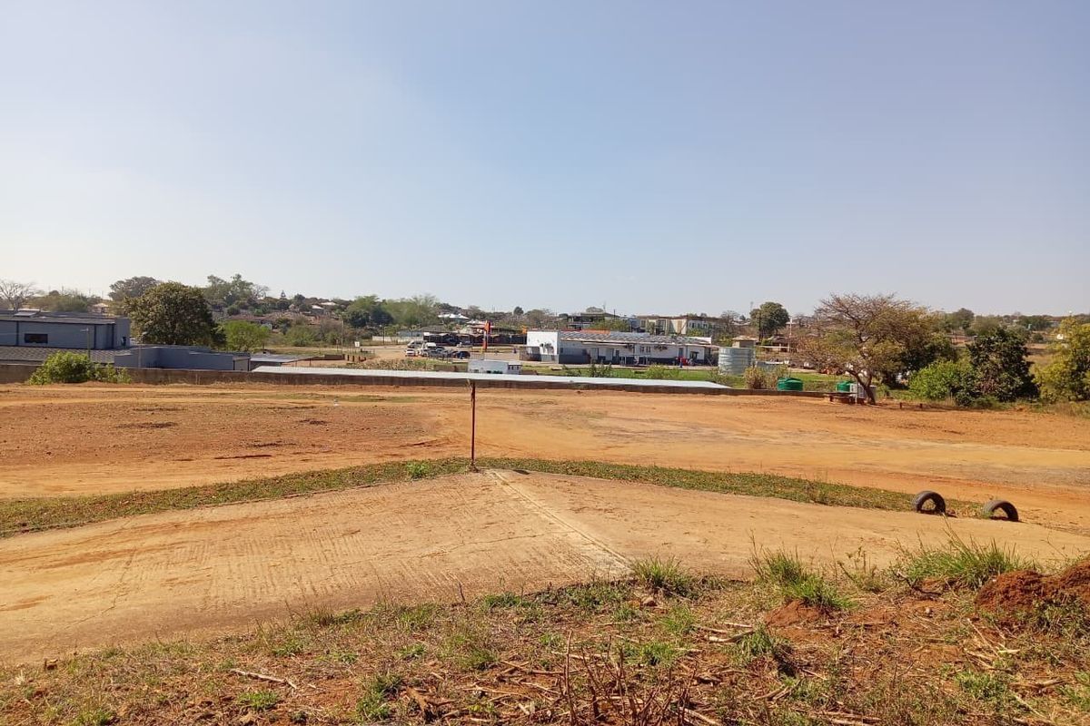 A view of the vacant commercial land showing the unpaved terrain and surrounding area.