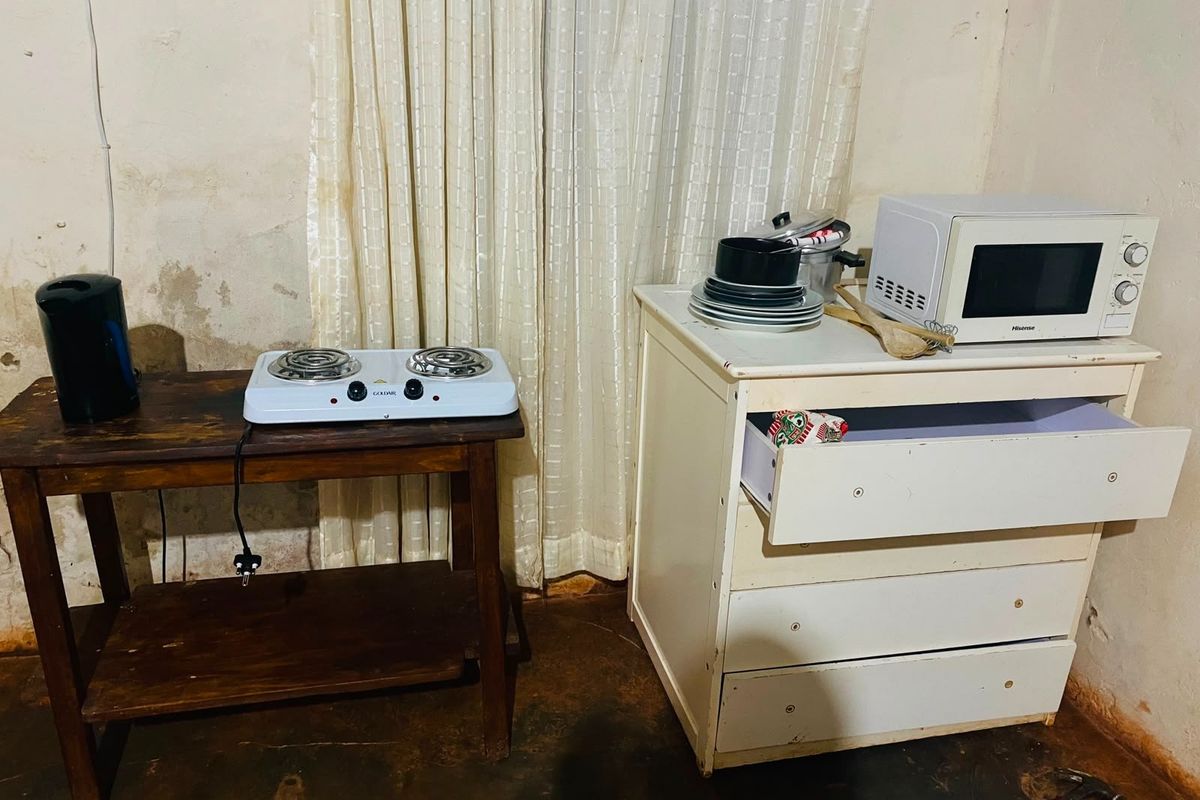 A basic kitchen setup featuring a portable electric hob and microwave, showing significant wear to the walls and flooring.