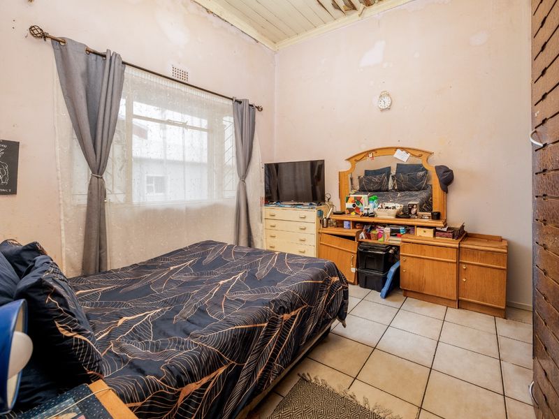 A bedroom featuring tiled flooring and a timber ceiling, currently requiring significant cosmetic repairs to the walls and ceiling.
