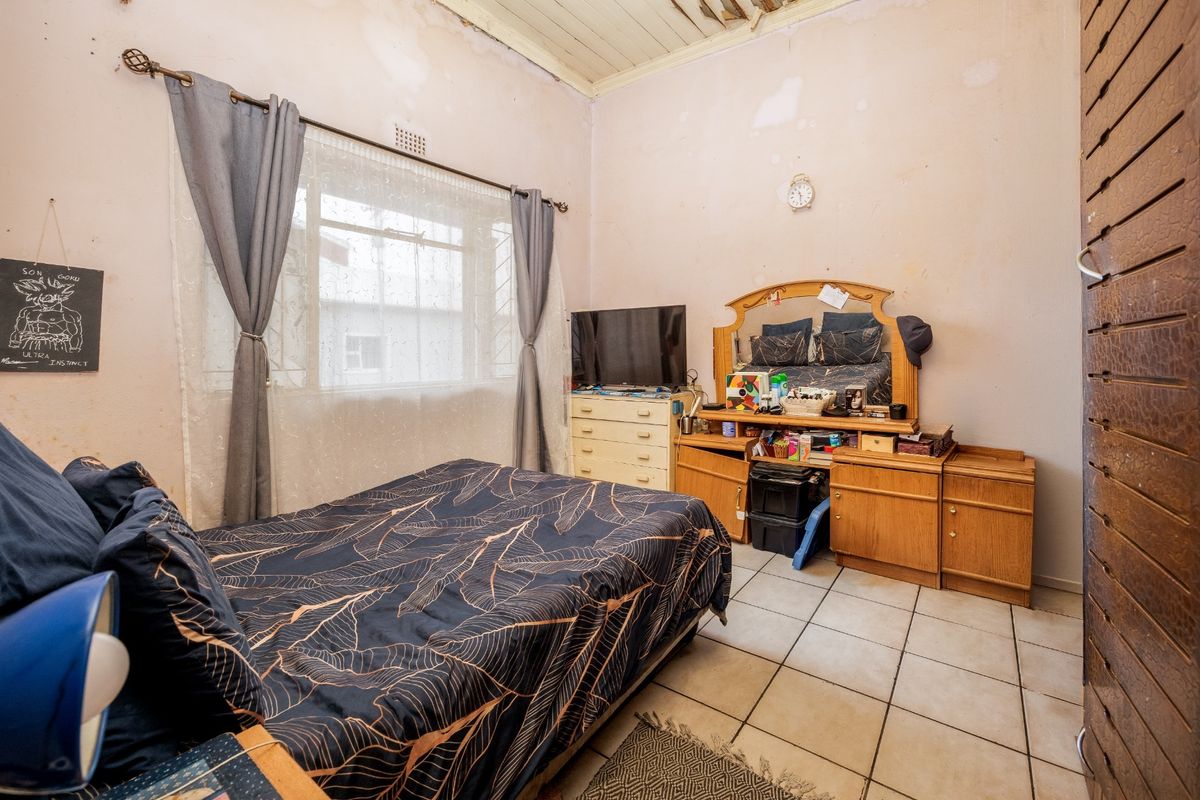 A bedroom featuring tiled flooring and a timber ceiling, currently requiring significant cosmetic repairs to the walls and ceiling.