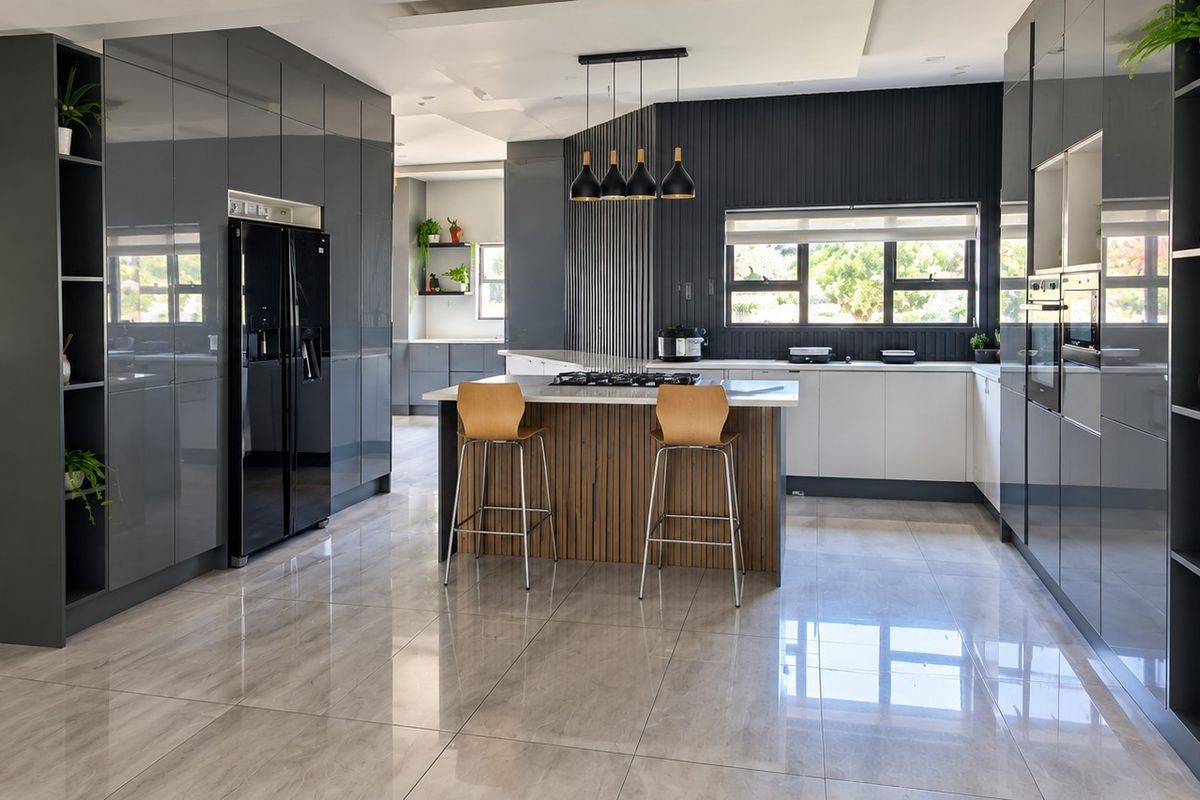 Modern, high-end kitchen featuring sleek glossy cabinetry, a central island with a gas hob, integrated appliances, and polished porcelain floor tiles.