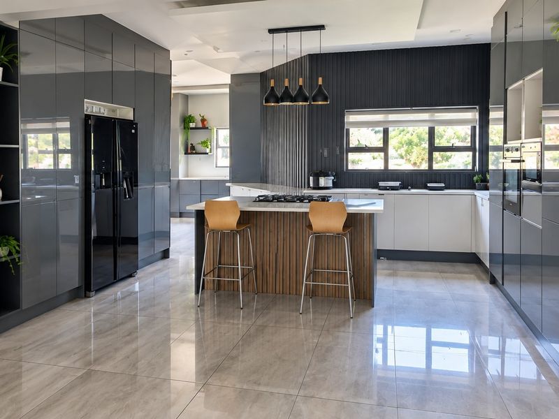 Modern, high-end kitchen featuring sleek glossy cabinetry, a central island with a gas hob, integrated appliances, and polished porcelain floor tiles.