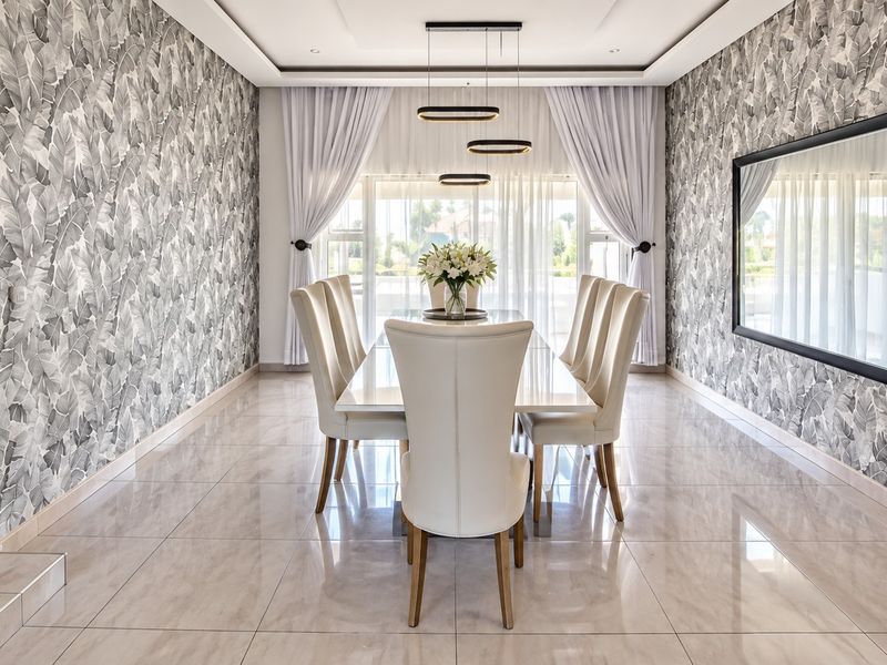 Elegant dining room featuring polished porcelain tile flooring, modern pendant lighting, and a large feature mirror, creating a sophisticated space for formal entertaining.