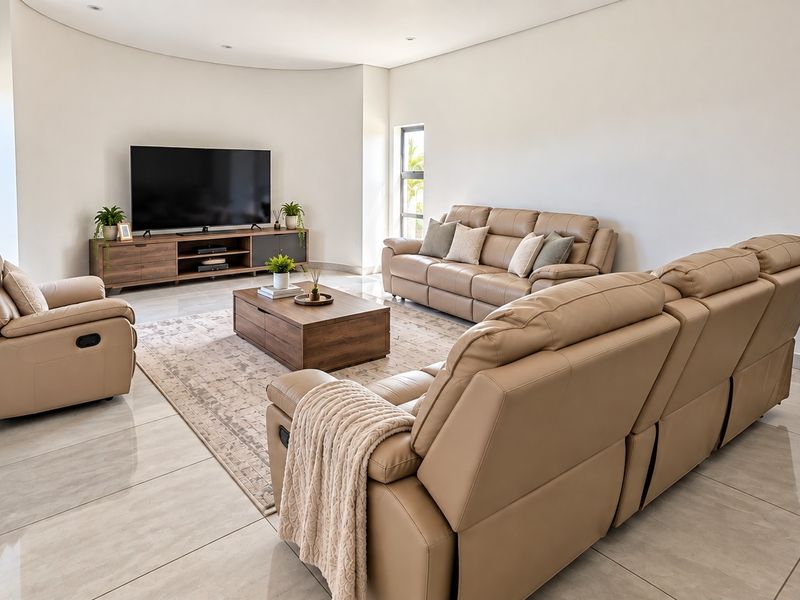 A spacious, modern living room featuring polished tiled flooring, a unique curved wall design, and recessed ceiling lighting.