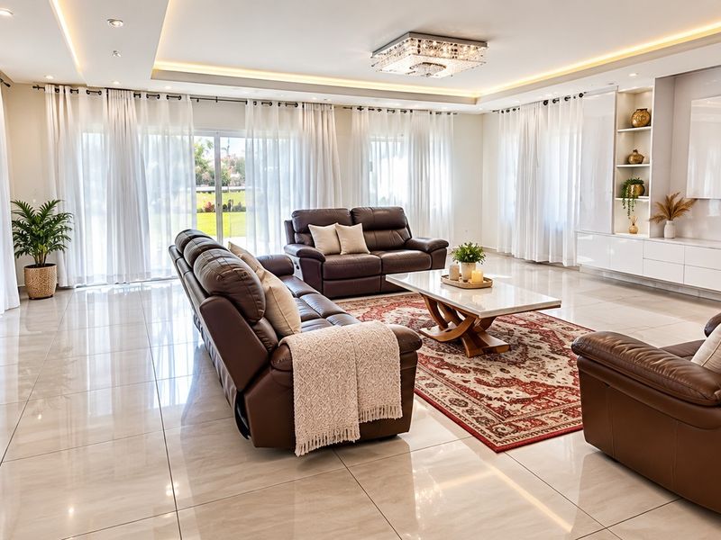 Spacious, modern living room featuring high-gloss porcelain tiles, recessed cove lighting, and a custom built-in media wall with integrated shelving.