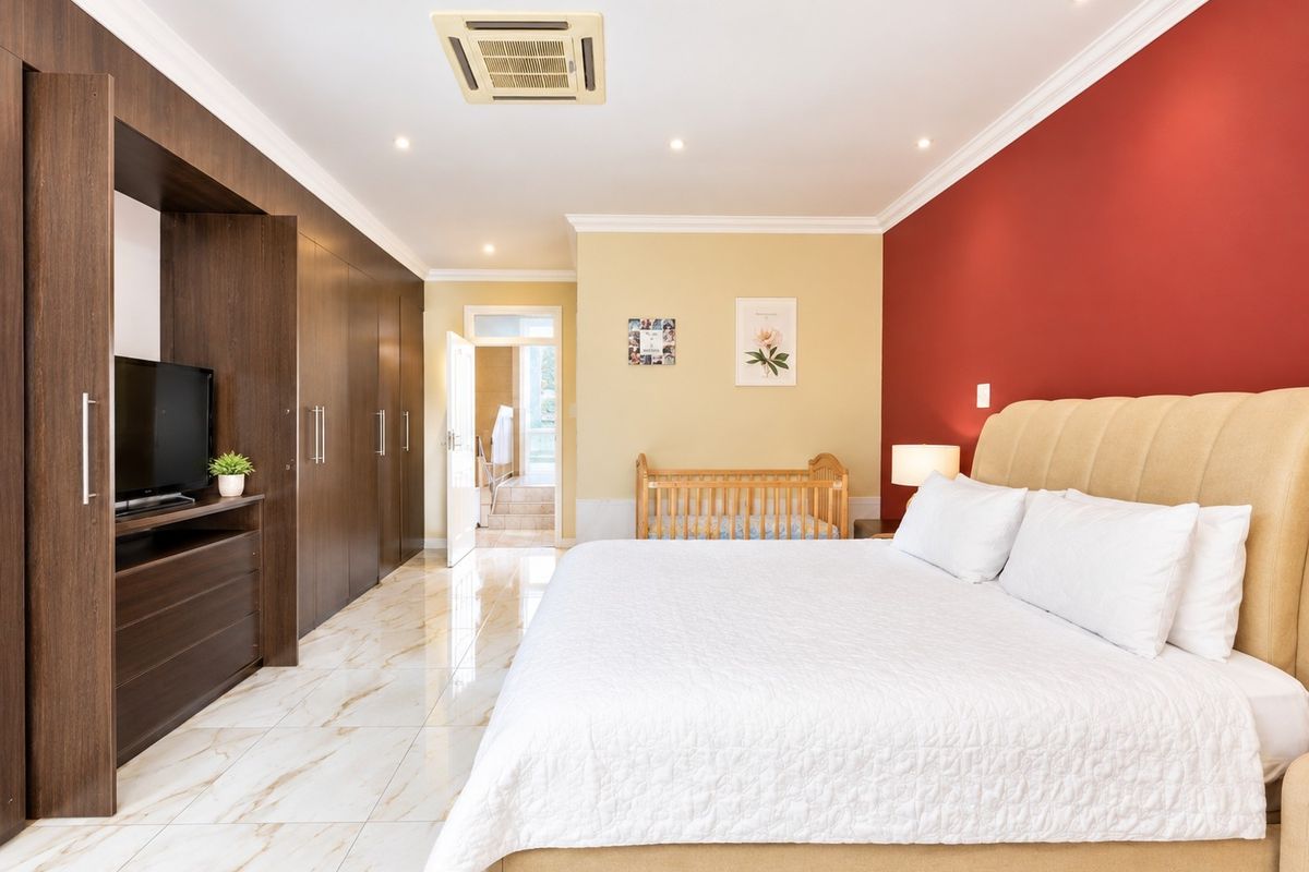 Spacious bedroom featuring marble-look tiled flooring, extensive built-in cabinetry, recessed lighting, ducted air conditioning, and direct access to an en-suite bathroom.