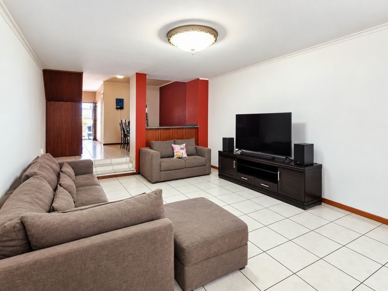 Open plan living area featuring tiled flooring, a breakfast bar, and neutral wall finishes, providing a functional space for relaxation and dining.