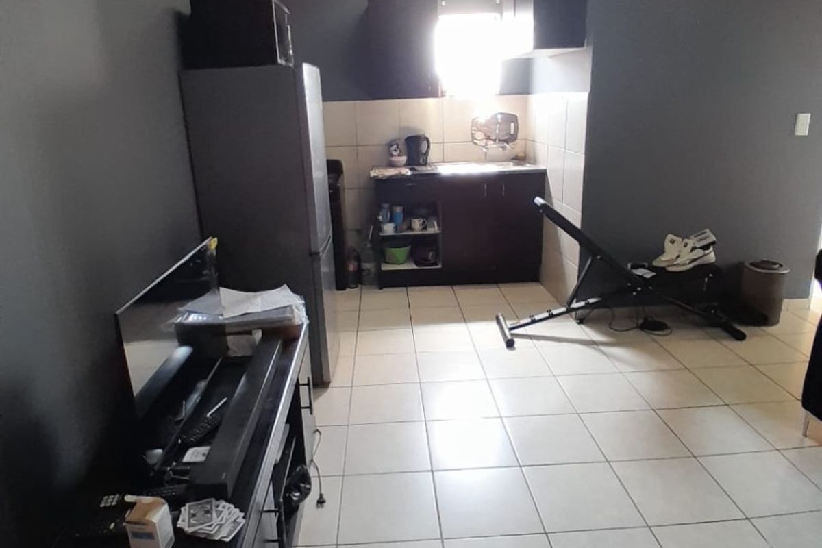 A compact kitchen area featuring dark cabinetry, tiled backsplash, and light-colored floor tiles, providing a functional space for meal preparation.