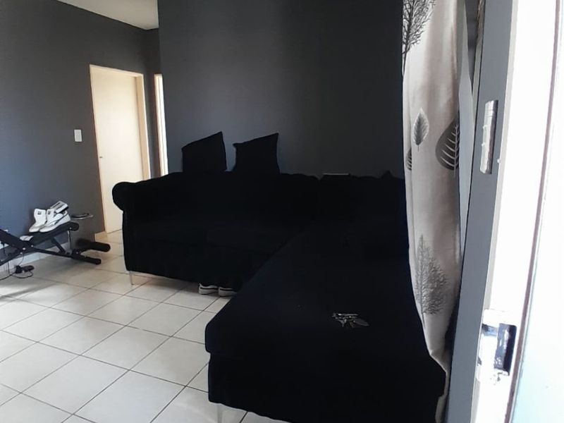 A living room area featuring tiled flooring and neutral grey wall paint, providing a functional space for relaxation.