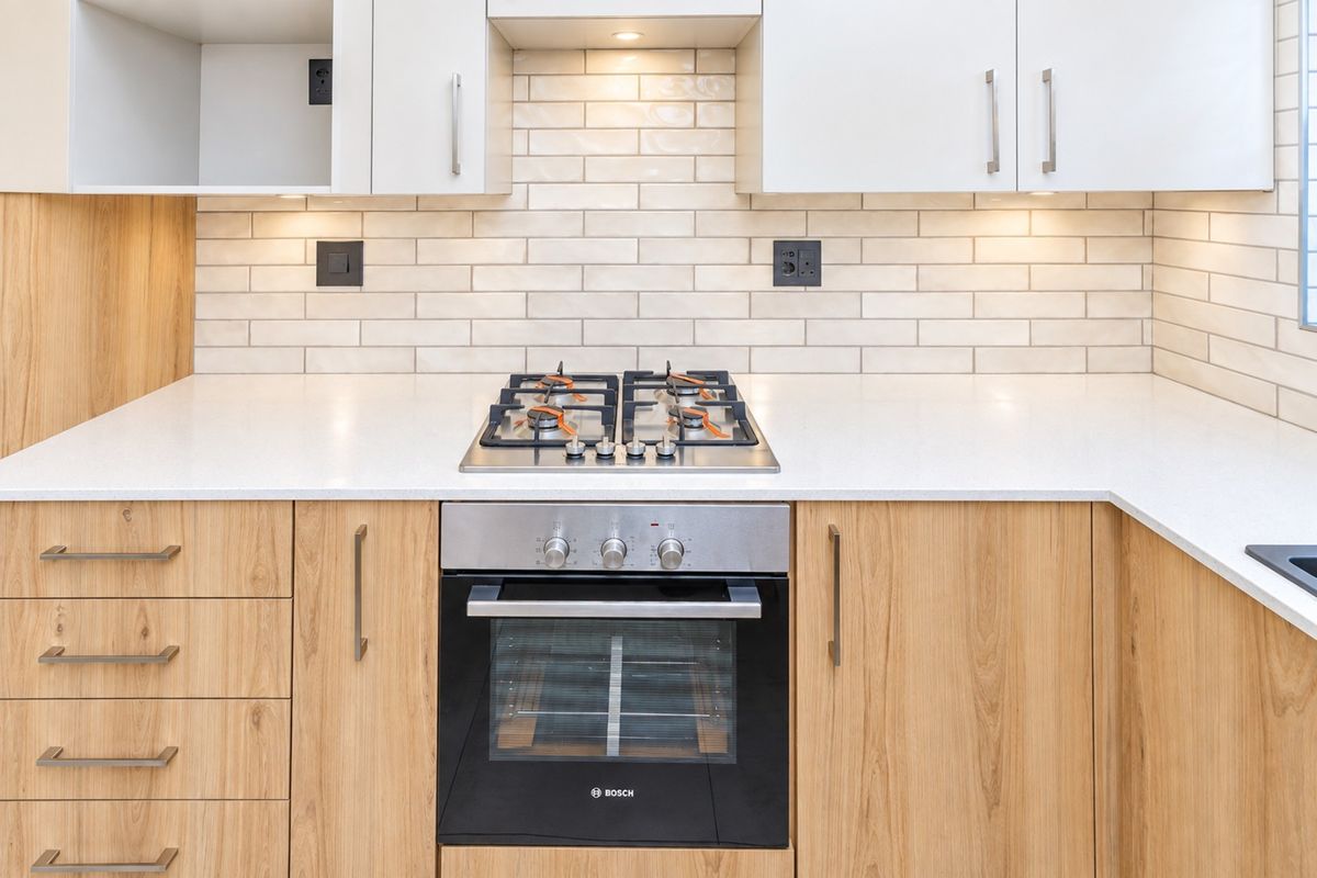 Modern kitchen featuring light wood cabinetry, white quartz countertops, a subway tile backsplash, and a built-in Bosch oven with a gas hob.