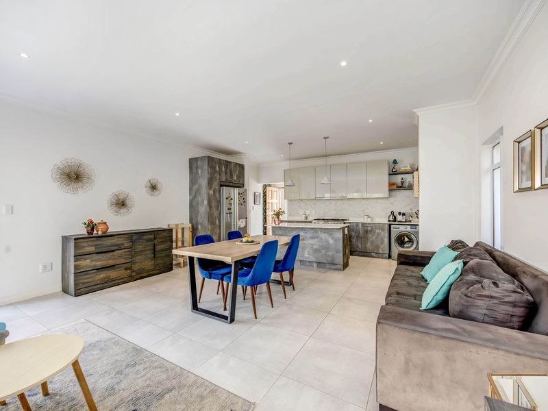 Spacious open-plan living and dining area featuring a modern kitchen with stone countertops, integrated cabinetry, and large format floor tiles.