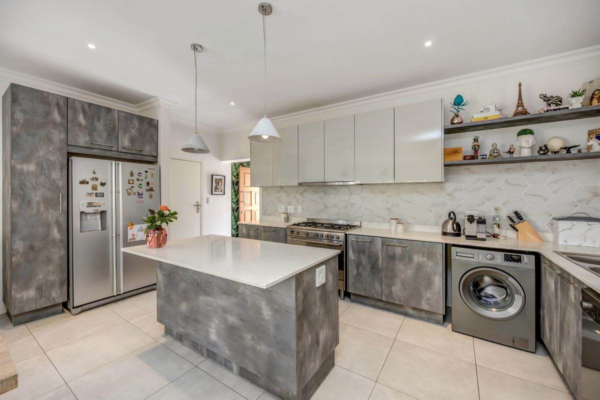 Modern kitchen featuring a central island, stone countertops, gas stove, hexagonal tile backsplash, and ample built-in cabinetry with a contemporary finish.