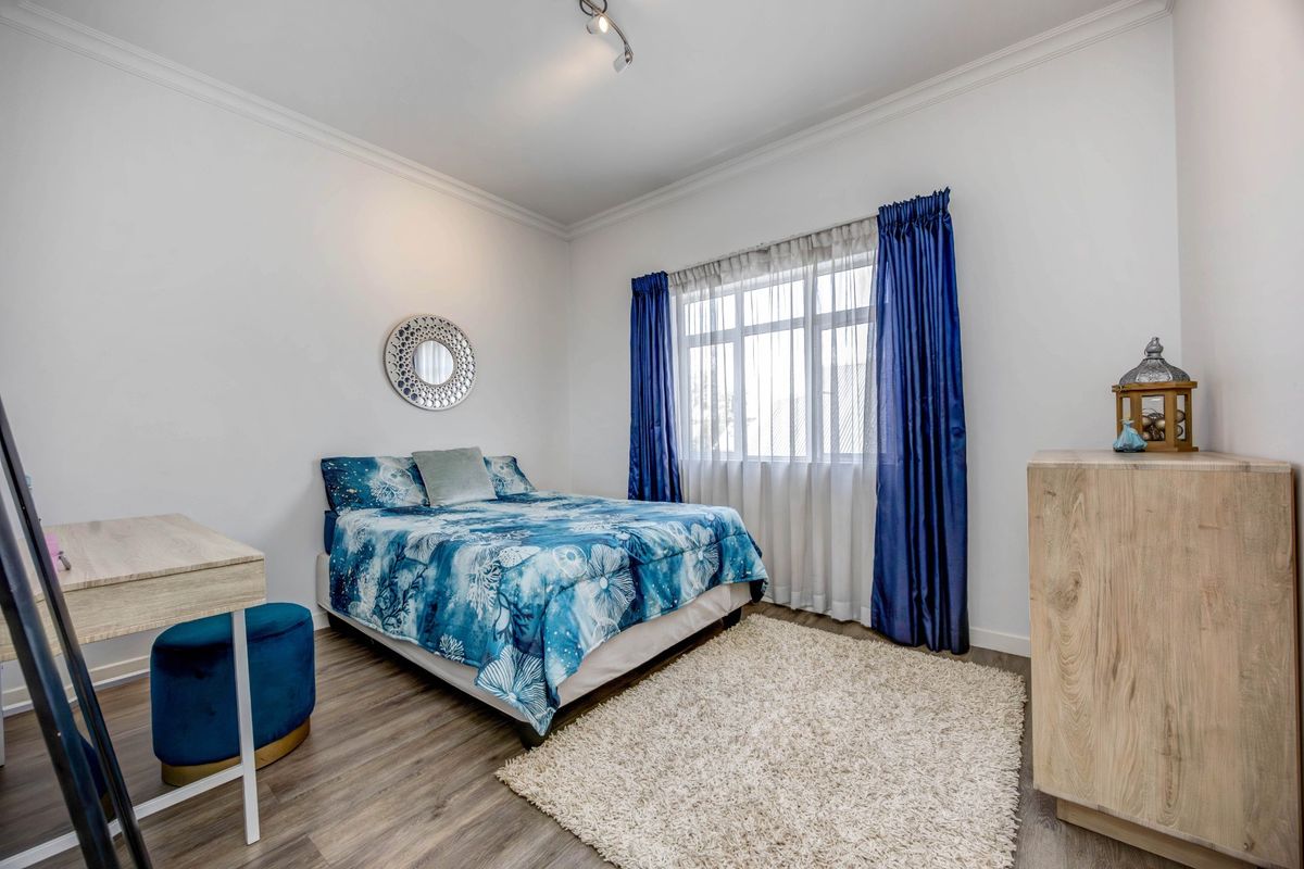 A well-maintained bedroom featuring laminate flooring, coved ceilings, and modern track lighting, offering a clean and neutral space.