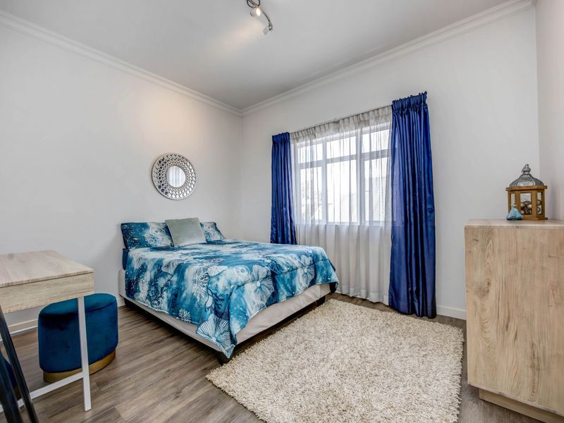 A well-maintained bedroom featuring laminate flooring, coved ceilings, and modern track lighting, offering a clean and neutral space.